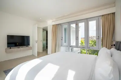 a white bedroom with a large bed and a large window at Villa Tara in Seminyak