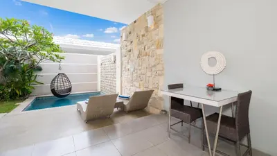 a dining room with a table and chairs and a swimming pool at Villa Larimar by Villa Finder in Legian