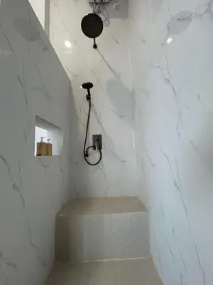 a bathroom with a shower with a bench and a light at Klissy Studio Villa in Kerobokan