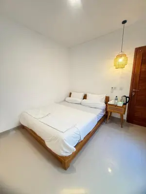 a large bed in a white room with a table at Home Stay Room in Bali Near Sanur Beach in Sanur