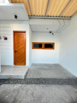 a room with a wooden door on a white wall at Home Stay Room in Bali Near Sanur Beach in Sanur