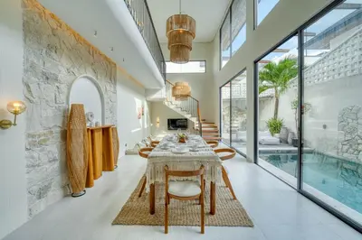 a dining room with a table and a swimming pool at Casa Amadeo Villas Seminyak in Seminyak
