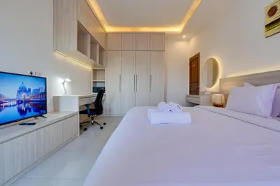 a white bedroom with a large bed and a flat screen tv at Stylish 2BR Villa Taman Seminyak 52 near Beach in Seminyak