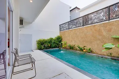a swimming pool in front of a house with a chair at Stylish 2BR Villa Taman Seminyak 52 near Beach in Seminyak