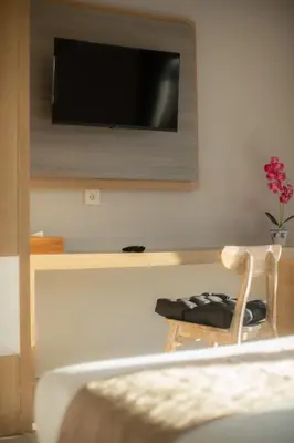 a room with a tv on a wall with a chair at Narmada House Seminyak in Seminyak