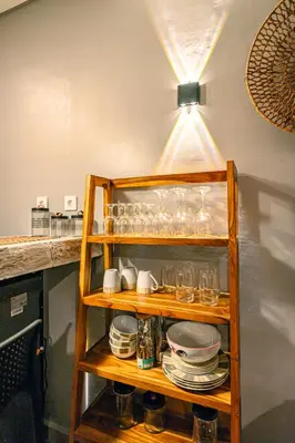 a shelf with glasses and plates and a light at Amshiga 1 in Jimbaran