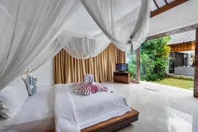a bedroom with a canopy bed and a television at Balima Villa in Seminyak