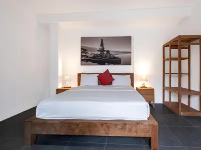 a bedroom with a white bed with a red pillow at Villa Melissa in Kerobokan