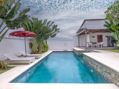 a swimming pool with a red umbrella and a house at Villa Melissa in Kerobokan