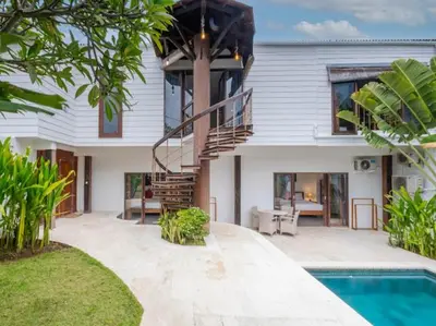 a white house with a staircase and a swimming pool at Villa Melissa in Kerobokan
