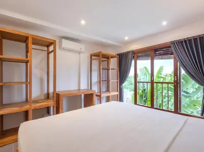 a bedroom with a white bed and a large window at Villa Melissa in Kerobokan