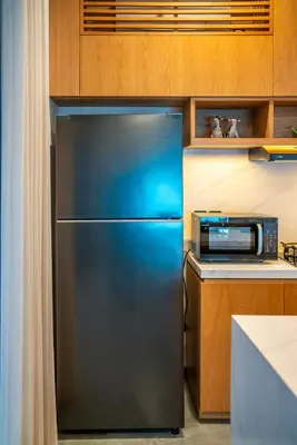 a stainless steel refrigerator in a kitchen with a microwave at Divija Villa by Unicorn Villas Bali in Kerobokan