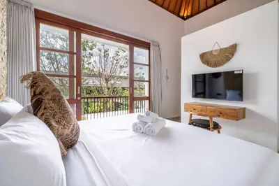 a bedroom with a large white bed with a television at 3BR Pool Villa in Berawa - Walk to Beach & Cafes in Canggu