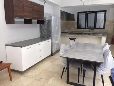 a kitchen with white cabinets and a table with chairs at Shivana Villa in Kerobokan