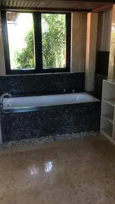 a bath tub sitting under a window in a bathroom at Shivana Villa in Kerobokan