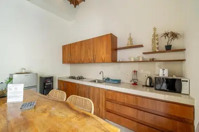 a kitchen with wooden cabinets and a table and a microwave at Modern Tropical 2BR Villa in Seminyak Kuta with Pool & Garden in Legian