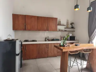a kitchen with wooden cabinets and a table and a refrigerator at Modern Tropical 2BR Villa in Seminyak Kuta with Pool & Garden in Legian