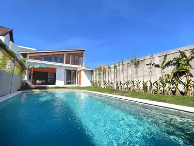 a swimming pool in front of a house at Villa Loba Sanur in Sanur