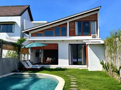 a house with a swimming pool in front of a house at Villa Loba Sanur in Sanur
