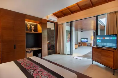 a bedroom with a large bed and a flat screen tv at Abia Villa Legian in Legian