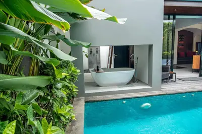 a bathroom with a bath tub next to a pool at Abia Villa Legian in Legian