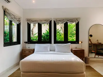 a bedroom with a large white bed with windows at Lovely 2 Bedroom Pool Villa Close to The Beach in Seminyak