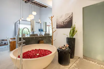 a bathroom with a large tub filled with red flowers at Semesta Collection Seminyak Villas in Seminyak