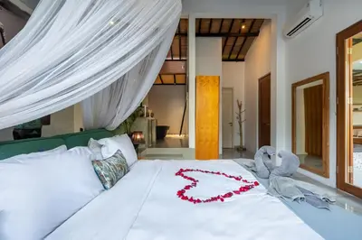 a bedroom with a white bed with a red flower on it at Semesta Collection Seminyak Villas in Seminyak