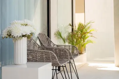 a group of wicker chairs and a vase with flowers at Villa Amare in Kerobokan