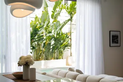a living room with a table and a large window at Villa Amare in Kerobokan