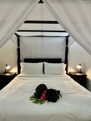 a white bed with two black hats on it at Will and Ray's at Lori Beach Inn in Seminyak