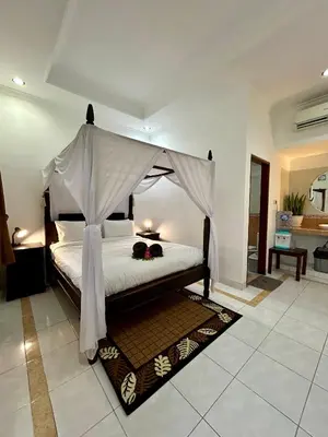a bedroom with a bed with a canopy at Will and Ray's at Lori Beach Inn in Seminyak