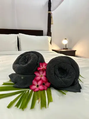 two towels and flowers on top of a bed at Will and Ray's at Lori Beach Inn in Seminyak