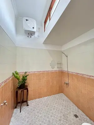 a bathroom with a shower and a plant on a table at Will and Ray's at Lori Beach Inn in Seminyak