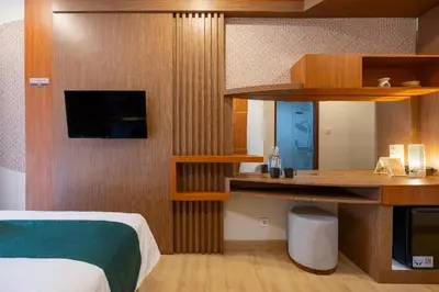a bedroom with a bed and a desk with a television at Cove Vin Stay Petanu in Pesanggaran