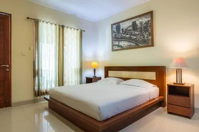 a bedroom with a bed and two lamps and a window at TheNadram Guest House in Kerobokan