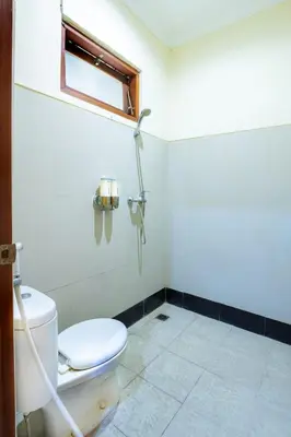a bathroom with a toilet and a window at TheNadram Guest House in Kerobokan