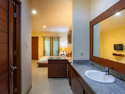a bathroom with a sink and a bed and a mirror at TheNadram Guest House in Kerobokan