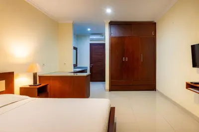 a bedroom with a bed and a desk and a door at TheNadram Guest House in Kerobokan