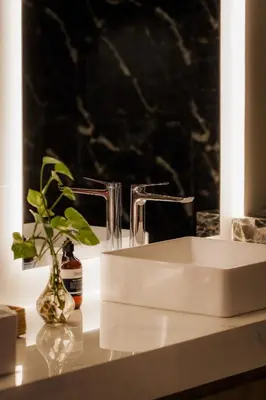 a bathroom sink with a vase with a plant on a counter at Villa Toku by BaliSuperHost in Seminyak