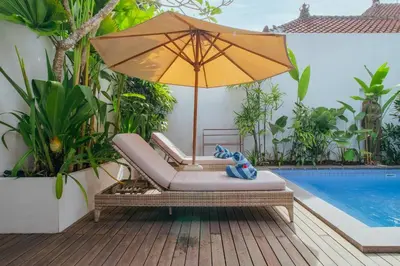 an umbrella sitting on a deck next to a swimming pool at Private 2 Br Pool Villa, 400m to Beach, Sleeps 4 in Seminyak