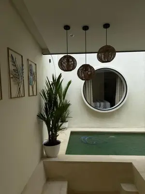 a bathroom with a pool with a mirror and a plant at Villa Bambu in Sanur
