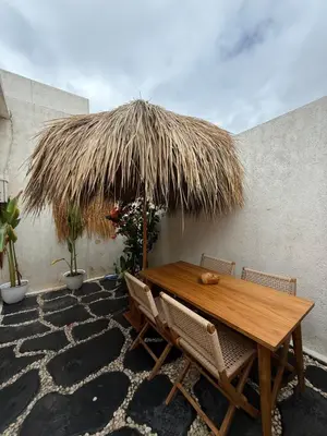 a wooden table and chairs under a straw umbrella at Villa Bambu in Sanur
