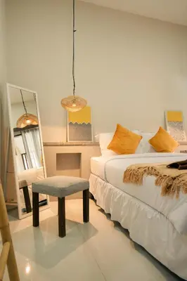 a bedroom with two beds and a chair and a mirror at Kuta Sekeca CoWorking Apartment Close to Kuta Beach in Jimbaran