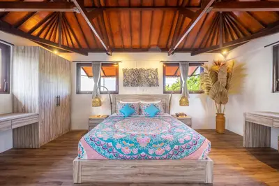 a bedroom with a large bed with blue pillows at Villa Lebah Seminyak in Seminyak