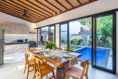 an open kitchen and dining room with a wooden table and chairs at Villa Lebah Seminyak in Seminyak