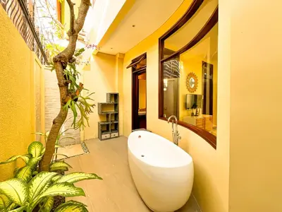 a bathroom with a bath tub next to a tree at Villa Michelle Bali in Seminyak