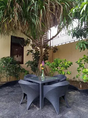 a table and chairs with a vase of flowers on it at Villa Michelle Bali in Seminyak