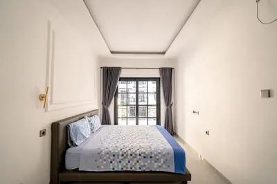 a bedroom with a bed in front of a window at Aurelia Home at Mogan Residence in Seminyak