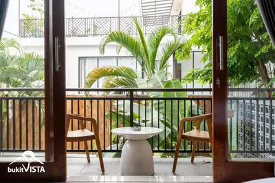 a balcony with two chairs and a table and a plant at Serayu Mertanadi by Bukit Vista in Seminyak